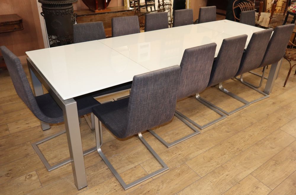 A modern large opaque glass and metal dining table and a set of twelve cloth-upholstered metal dining chairs, W.260cm extended D.90cm H